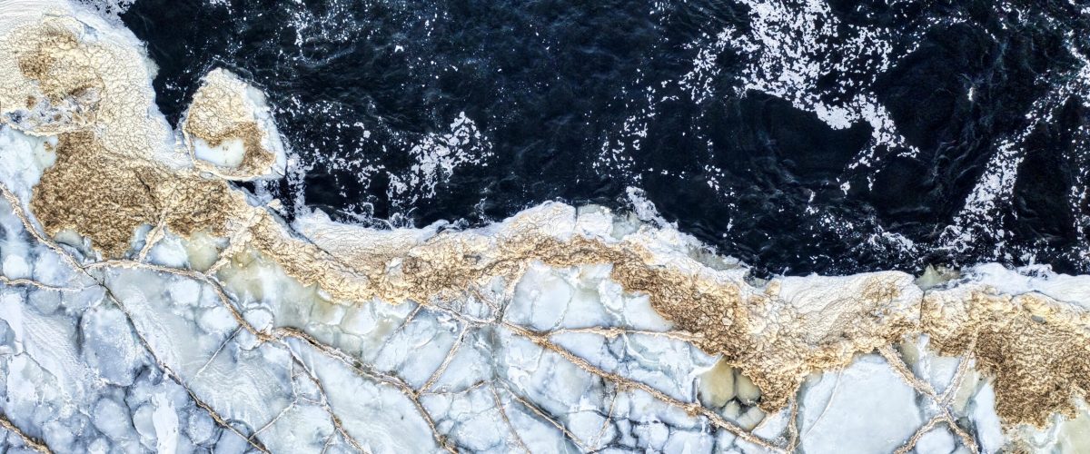 Stunning aerial shot of frozen shoreline with cracked ice patterns in Minneiska, MN.